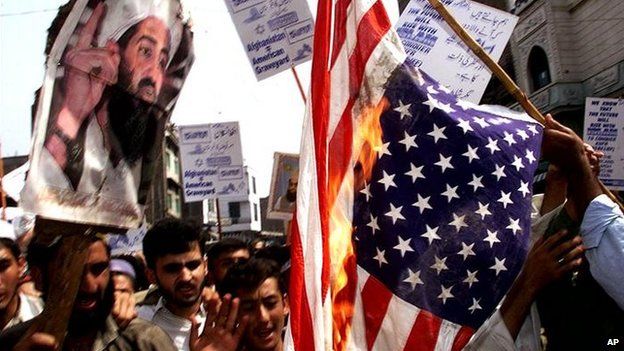 Protesters holding a picture of Osama Bin Laden burn the US flag in Peshawar, Pakistan (23 September 2001)