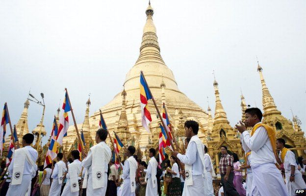 Buddhist devotees carry flags as they take part in a ceremony at the Shwedagon pagoda on the full moon day of Kasone Festival to mark Buddha's birthday in Yangon on 13 May 2014.