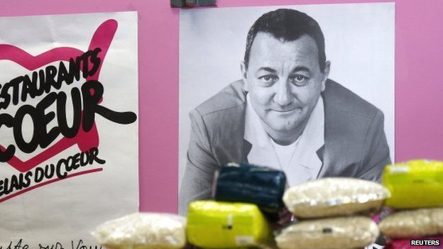 Packages of rice are displayed in front of a picture of late French comic Coluche at a food distribution centre for the "Les Restos du Coeur" (Restaurants of the Heart) in Paris on 24 November 2014.