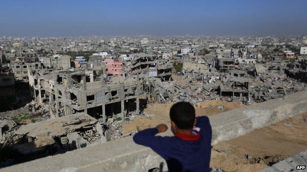 Palestinian boy looks at rubble of houses