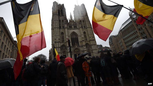 Onlookers wave Belgium flags as the coffin arrives at the Saint Michael and Saint Gudula Cathedral in Brussels