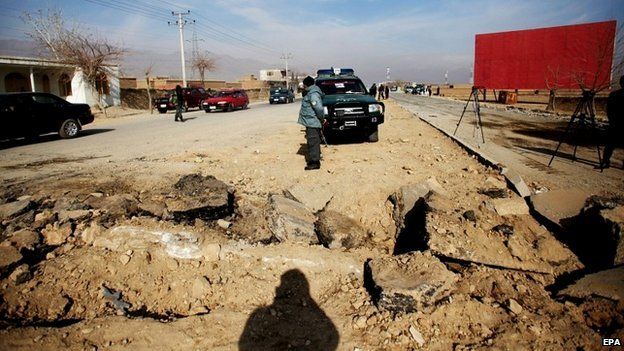 Afghan security officials stand near the site of an attack on a US convoy near Bagram air base in Afghanistan - 13 December 2014