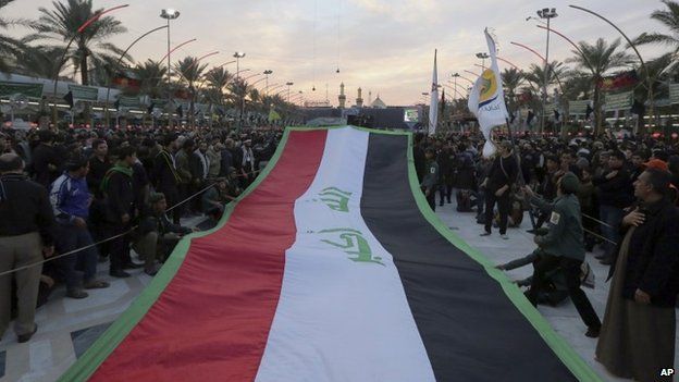 Pilgrims carrying a huge Iraqi flag through the streets