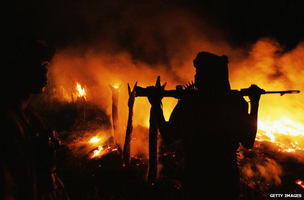 Anti-government fighters watch the Darfur village of Chero Kasi burning after it was allegedly set alight by a pro-government militia, 7 September 2004