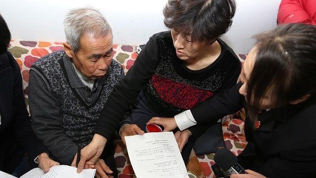 The judge of the higher people's court delivers retrial files to Hugjiltu's parents (C) in Hohhot, northern China's Inner Mongolia autonomous region on December 15, 2014