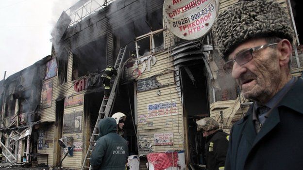 Firefighters and emergency workers examine the burned market pavilions in downtown Grozny