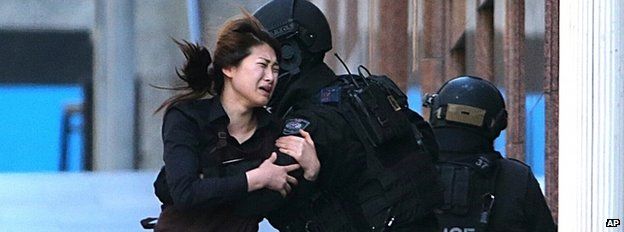 An escaping hostage is caught by a policeman in Sydney, 15 December