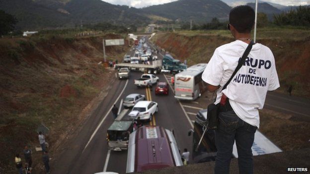 A vigilante stands guard on a bridge during a blockade on a highway near the town of Uruapanon 14 December, 2014.