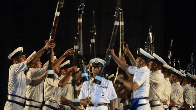 Indian navy sailors throw their rifles towards each other as an officer walks past during a rehearsal for Navy Day celebrations in front of The Gateway of India in Mumbai on 2 December 2013