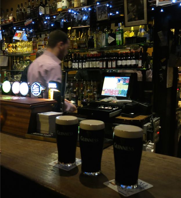 Three pints of Guinness on a bar