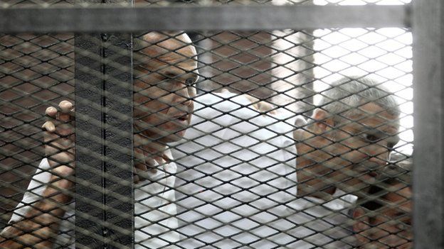 Photo from 23 June 2014 shows Australian journalist Peter Greste (L) and Canadian-Egyptian journalist Mohammed Fahmy (C) standing inside court"s cage