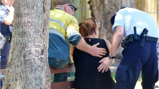 Police comfort a woman outside the house in Cairns (19 Dec 2014)