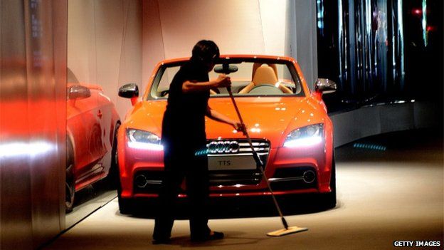 A cleaner sweeps the floor at a luxury auto showroom in Beijing on 15 September, 2014