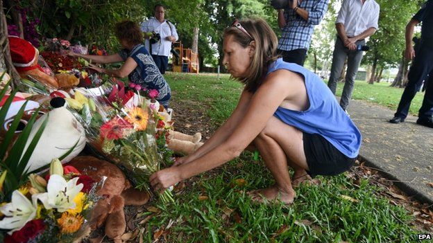 A woman lays flowers in memory of eight children murdered in Cairns
