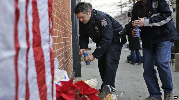 Police officers bring candles to an impromptu memorial near the site where two police officers were killed in the Brooklyn borough of New York, Sunday, Dec. 21, 2014