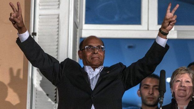 Tunisian presidential candidate Moncef Marzouki makes the V for victory sign on a balcony