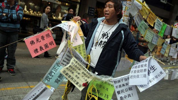 Протестующий срезает ряд знаков, чтобы позволить большему количеству людей прийти на место протеста в поддержку демократии в районе Козуэй-Бэй в Гонконге