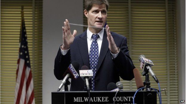 Milwaukee County District Attorney John Chisholm demonstrates bullet trajectory at news conference Monday, 22 December, 2014.