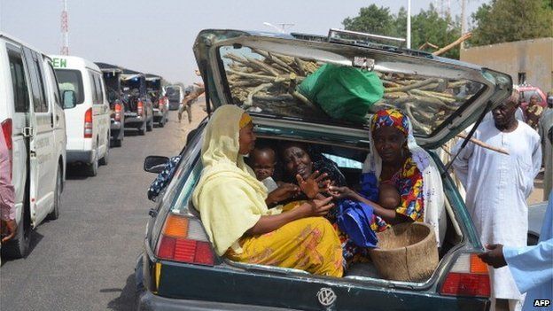 Women and children gather into a car's trunk as villagers flee the village of Jakana, outside Maiduguri, Borno State, Nigeria, on 6 March 2014