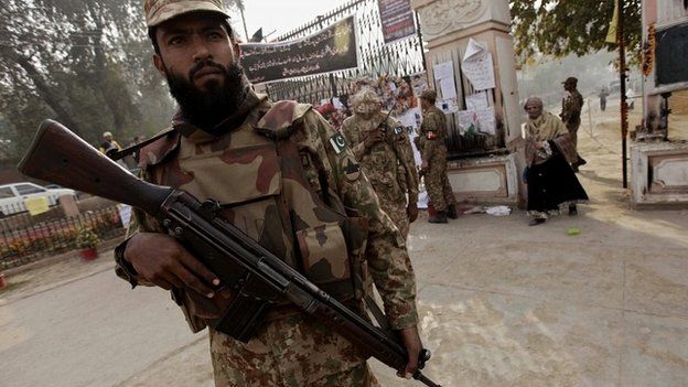 Members of the Pakistani military stand guard outside the recently attacked Army Public School in Peshawar - 24 December 2014