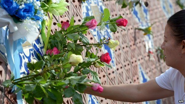 A Thai relative of a tsunami victim places roses on the Ban Nam Khem tsunami memorial park wall on the tenth anniversary of the 2004 tsunami in Phang-nga province on December 26, 2014