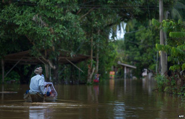 Local residents use a boat to cross the flooded streets in Pengkalan Chepa, near Kota Bharu on December 27, 2014