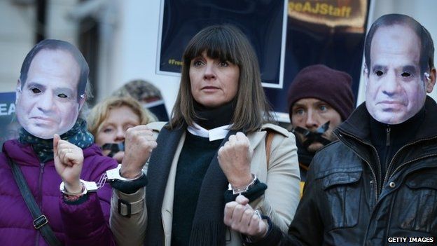 Al-Jazeera journalist Sue Turton (C) stands handcuffed to fellow supporters, wearing masks depicting President el-Sisi, as they demonstrate in support of jailed colleagues outside the Egyptian embassy on December 29, 2014 in London, England