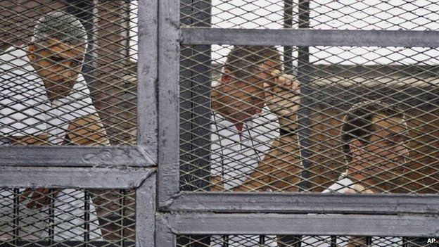 from left, Mohammed Fahmy, Canadian-Egyptian acting bureau chief of al-Jazeera, Australian correspondent Peter Greste, and Egyptian producer Baher Mohamed appear in a defendants' cage along with several other defendants during their trial on terror charges at a courtroom in Cairo. The United States and other countries on Wednesday, 5 November 2014