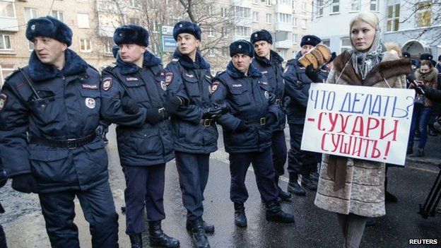 A supporter of opposition leader and anti-corruption blogger Alexei Navalny stands next to policemen blocking a street near a court building during his hearing in Moscow December 30, 2014