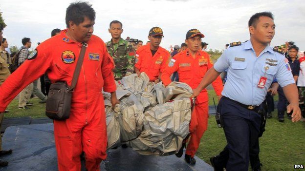 Indonesian air force crew carry what is believed to be slide from missing plane to military base in Pangkalan Bun - 30 December