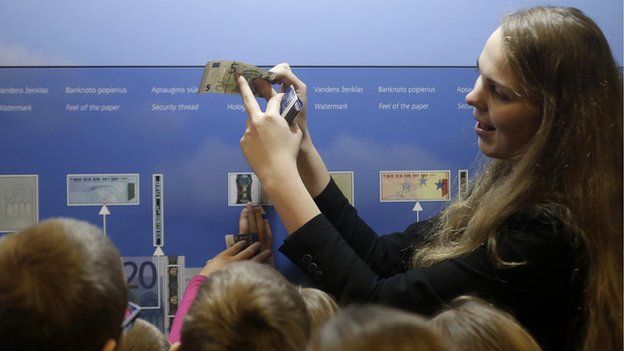 A guide shows the security features of euro banknotes to students in Vilnius 17 Dec 14