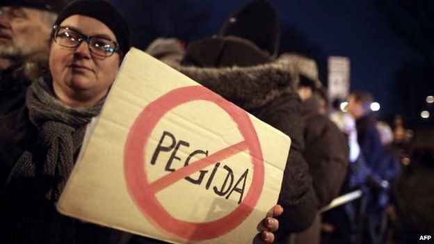 A woman protesting against the anti-Islam party Pegida holds up a sign