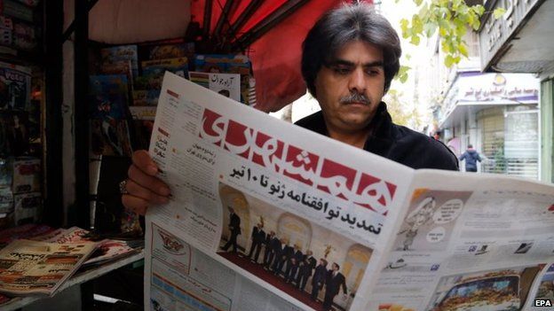 An Iranian man reads a copy of the Hamshahri newspaper, whose front page shows a picture of Iranian Foreign Minister Mohammad Javad Zarif with counterparts from the P5+1 in Geneva (25 November 2014)