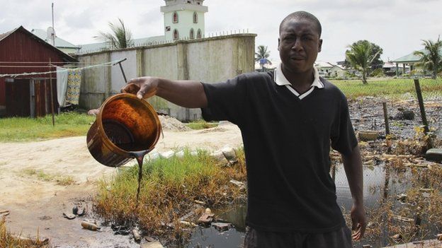 A villager shows a bucket of of crude oil spill at the banks of a river, after a Shell pipeline leaked, in the Oloma community in Nigeria"s delta region on 27 November 2014.