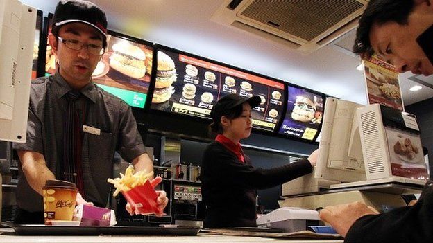 An employee serves French fries to a customer at a McDonald's restaurant in Tokyo on December 16, 2014.