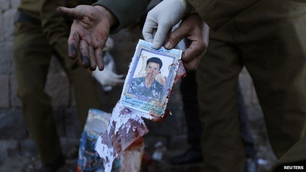 A policeman holds up the photo of one of the victims of the bomb attack in Sanaa (7 January 2015)