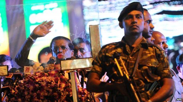 Sri Lanka"s main opposition presidential candidate Maithripala Sirisena (L) addresses his supporters from behind a bullet proof screen during an election rally in Colombo on January 5, 2015.