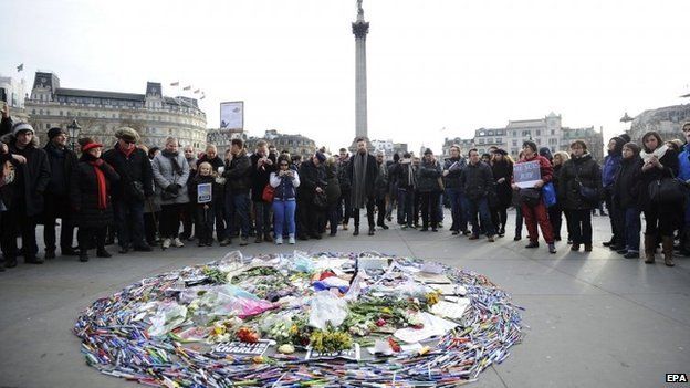 Demonstrators look at tributes in support of the Charlie Hebdo magazine victims during a solidarity gathering in Trafalgar square