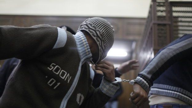 Defendants enter a cell a few minutes before they hear the verdict at a court in Cairo January 12, 2015