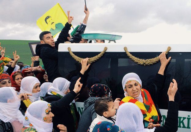 Kurdish women march alongside a convoy carrying the body of Gulsum Cam, a 24-year-old Turkish Kurdish PKK guerrilla killed fighting Islamic State in Kobane. A flag displaying the face of imprisoned PKK leader Abdullah Ocalan flies among the crowd.