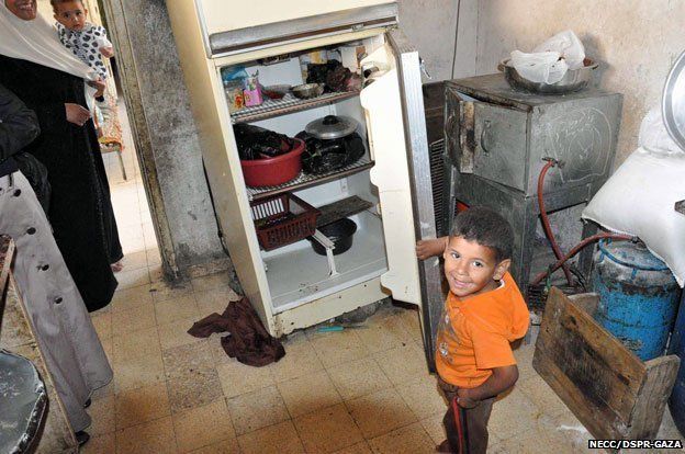 A young boy shows the inside of his family's fridge.