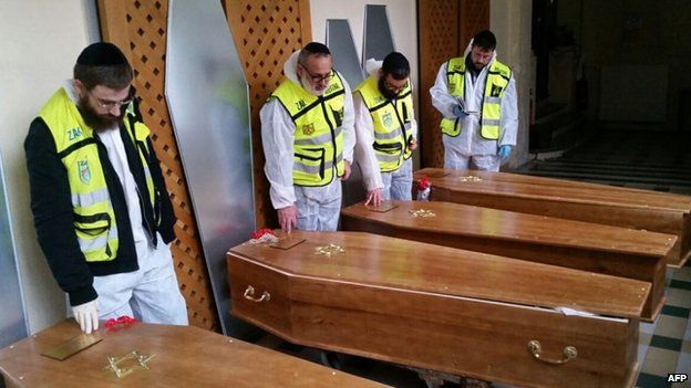 Zaka emergency response members stand next to the coffins of the four French Jews killed in the Paris attacks