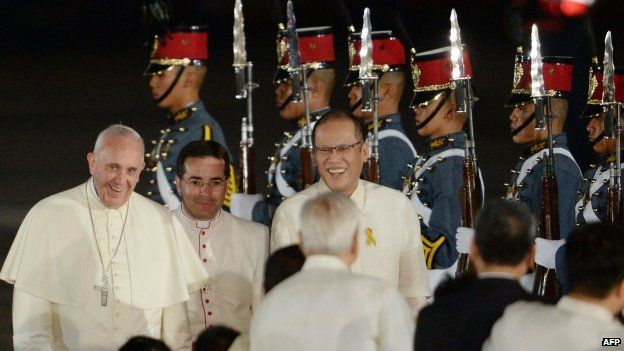 Pope Francis (left) is greeted by children while Philippine President Benigno Aquino (back right) looks on