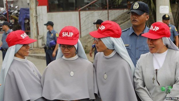 Roman Catholic nuns from Sacred Heart Jesus Parish wait for the motorcade of Pope Francis to pass along a main street in Manila (15 January 2015)