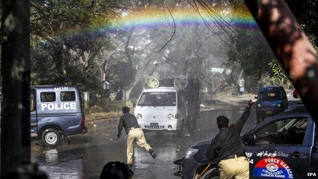 A rainbow appears over the street as Pakistani police use water cannon vehicles to disperse protesters in Karachi, Pakistan, 16 January
