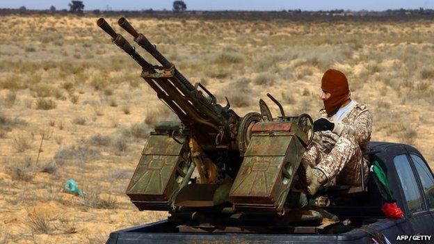 A fighter from the Fajr Libya (Libya Dawn) militia sits on a pick up truck mounted with a machine gun during clashes with forces loyal to Libya