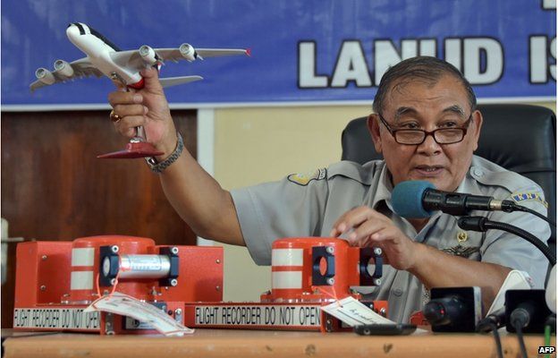 Tatang Kurniadi, the head of the National Transportation Safety Committee (KNKT), speaks to journalists while using samples of the flight data recorder (FDR) (pictured at R on table) and cockpit voice recorder (CVR) (L on table) during a press conference in Pangkalan Bun on 13 January 2015