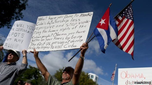 Jose Ignacio Jimenez (centre) holds a US flag and a Cuban one as he joins others opposed to US President Barack Obama's announcement of a change to the US Cuba policy on 20/12/2014 in Miami, Florida