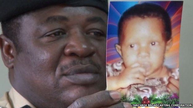 A policeman holds up a picture of missing albino girl Pendo Emmanuelle Nundi