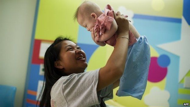 Thai surrogate mother Pattaramon Chanbua (L) with her baby Gammy, born with Down Syndrome, at the Samitivej hospital, Sriracha district in Chonburi province on August 4, 2014